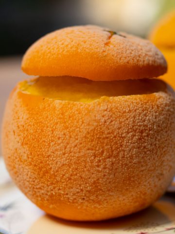 frozen orange filled with sorbet on a plate with spoon