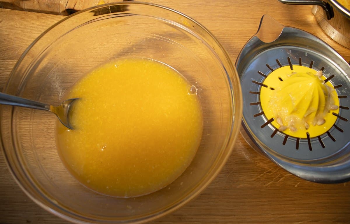 bowl containing orange juice mixture next to juice squeezer