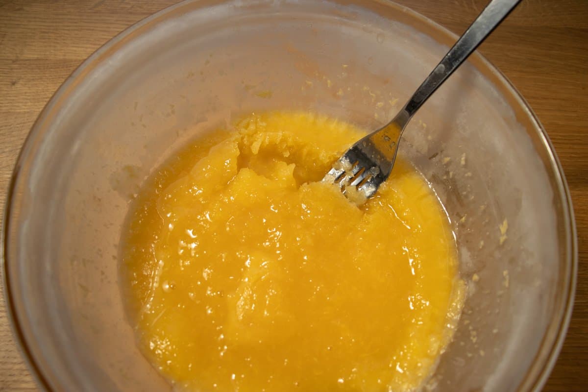 half frozen orange sorbet in a bowl being broken up with a fork