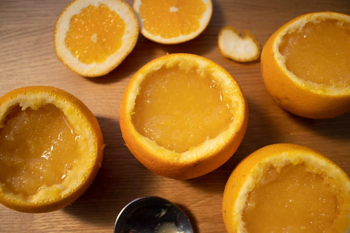 orange skins filled with half frozen sorbet next to sliced off orange tops