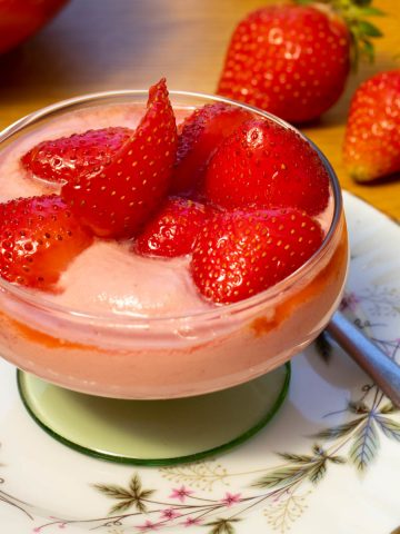 raspberry cream topped with strawberries in a glass bowl.
