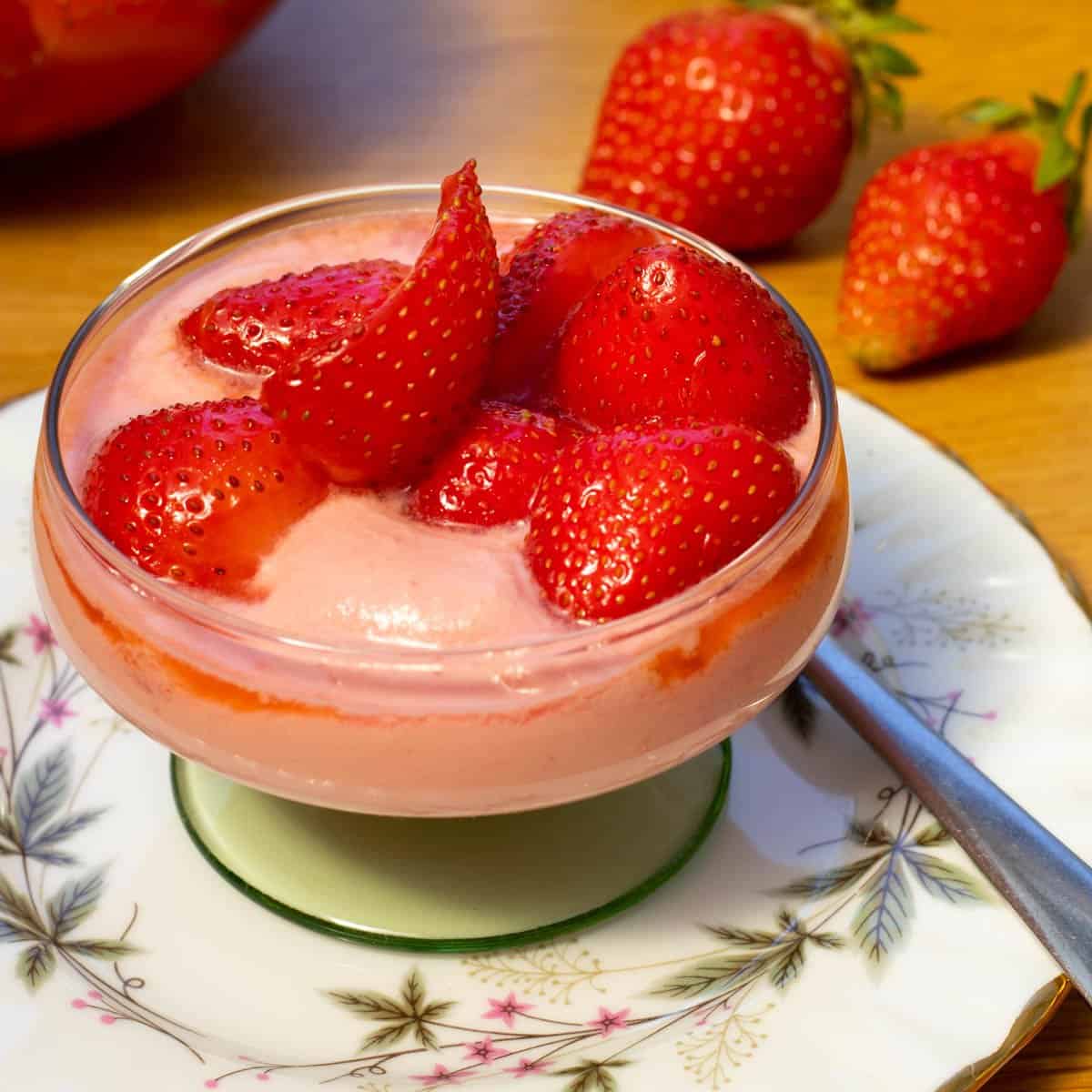 raspberry cream topped with strawberries in a glass bowl.