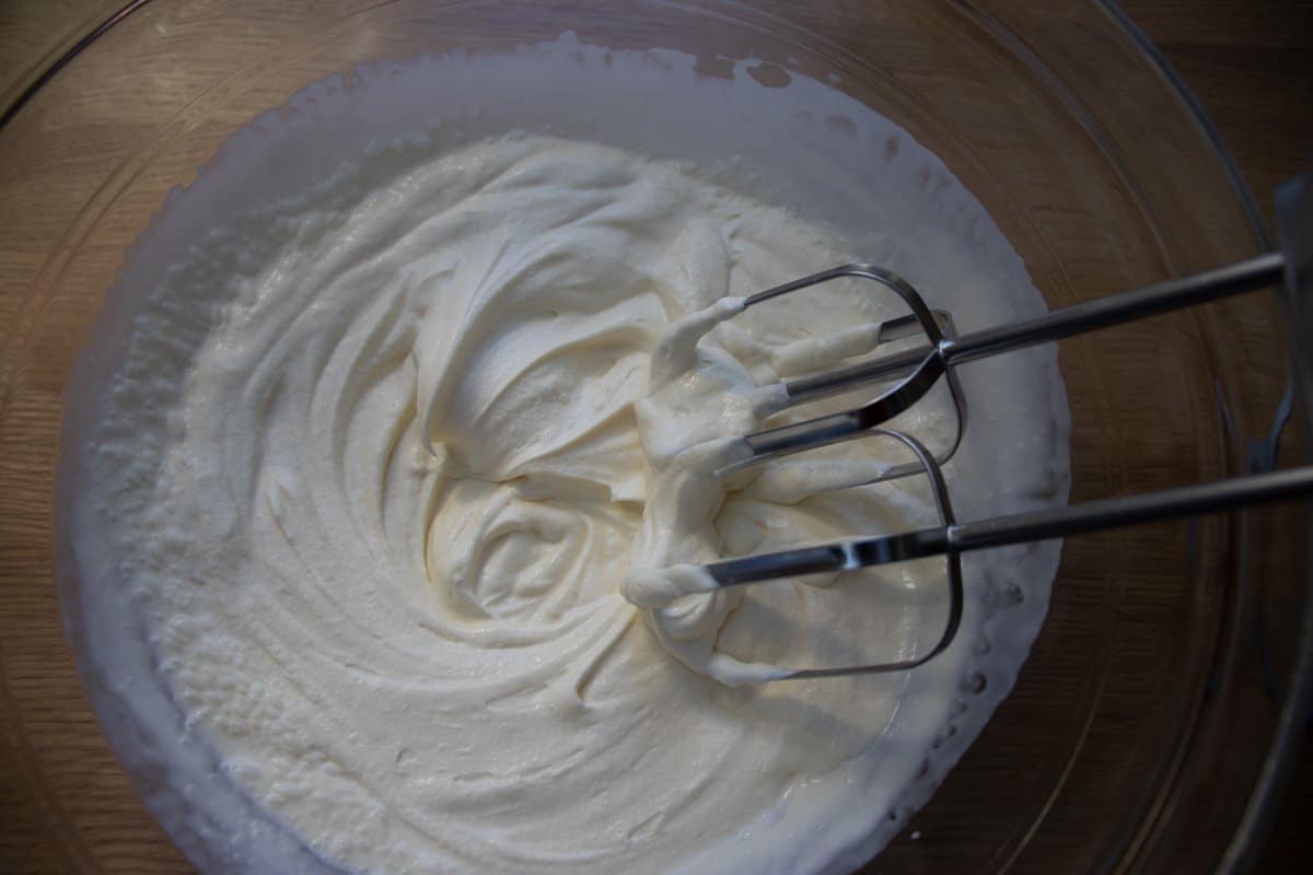 Double cream being whisked in a glass bowl.