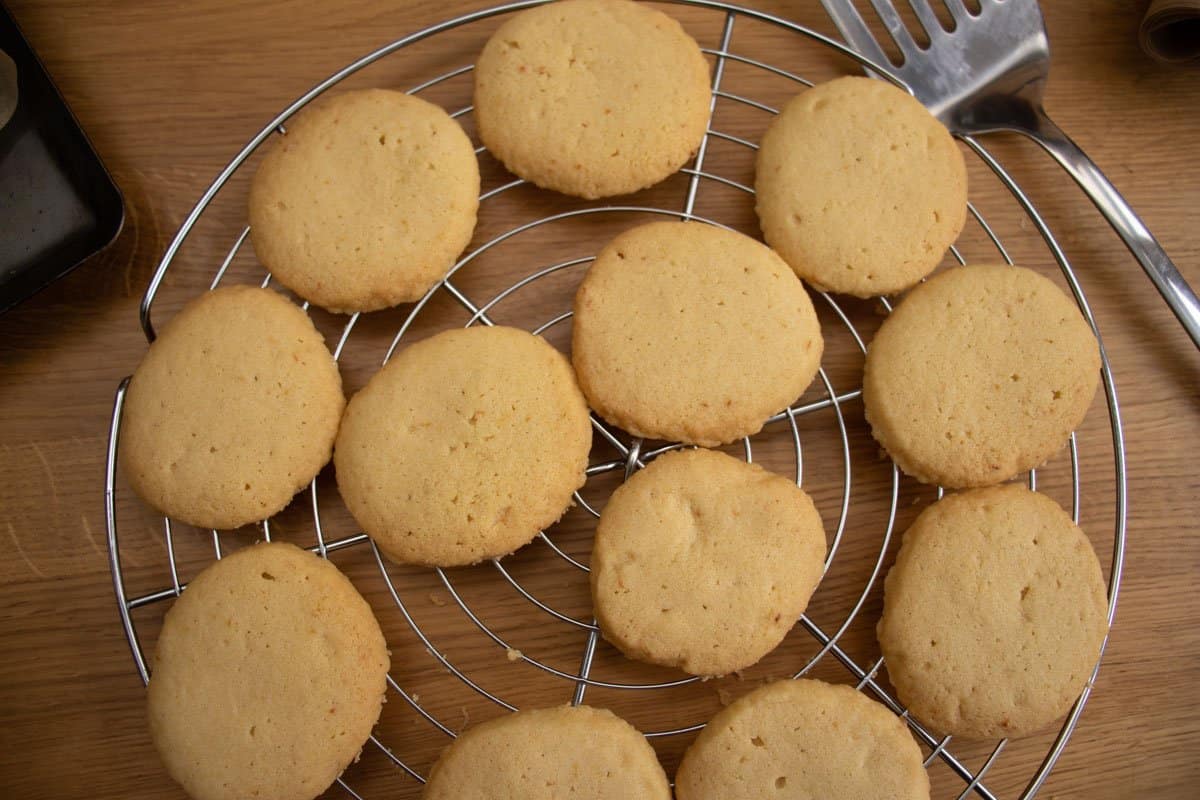 Baked lemon butter biscuits on metal cooling rack with metal slice