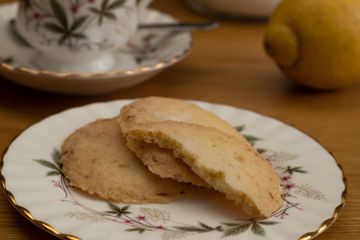 Lemon butter biscuits on plate with teacup and saucer and lemon