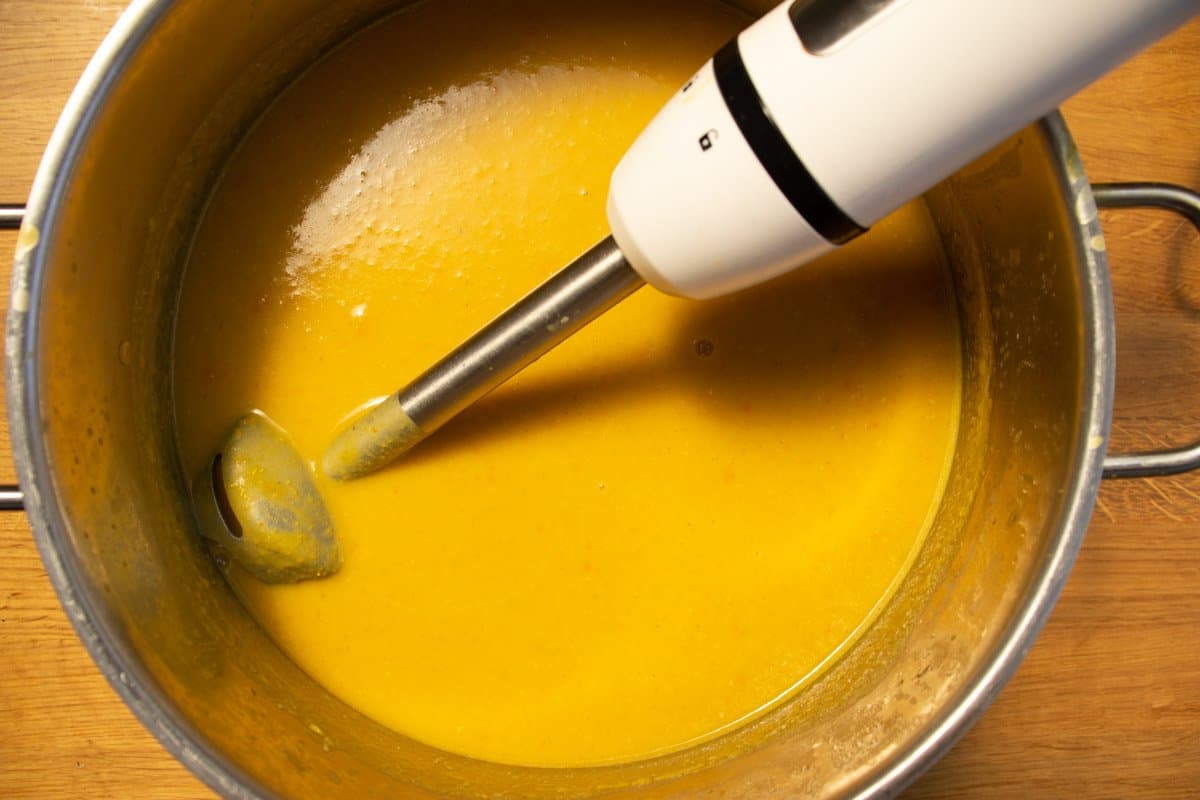 Blended Mediterranean lentil soup in a saucepan with a blender.