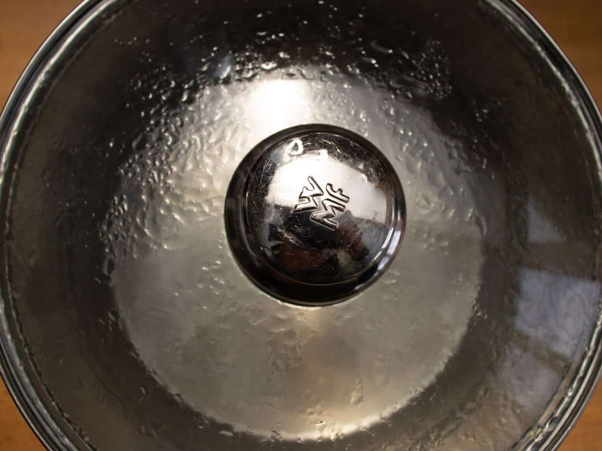 Water boiling in a saucepan with lid on.