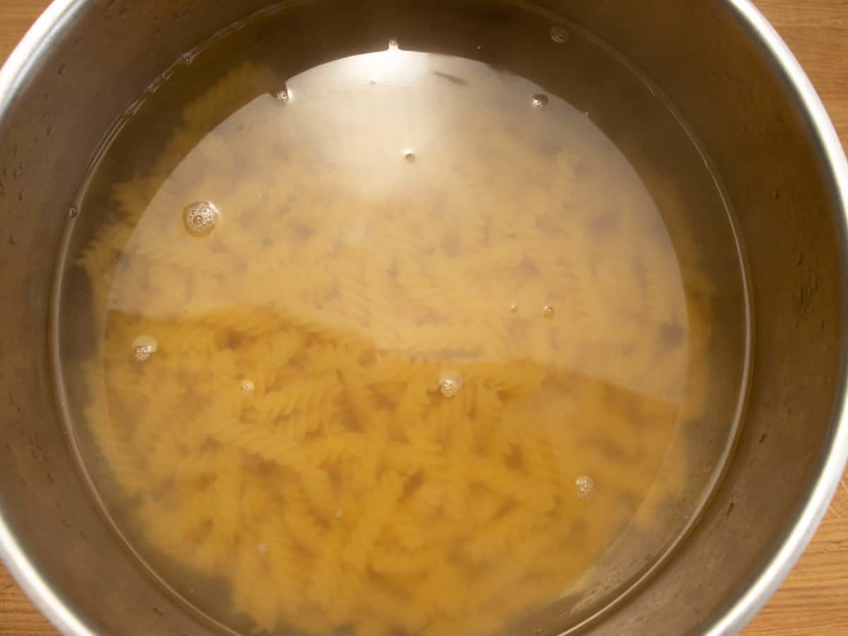 Fusilli pasta in water in saucepan.