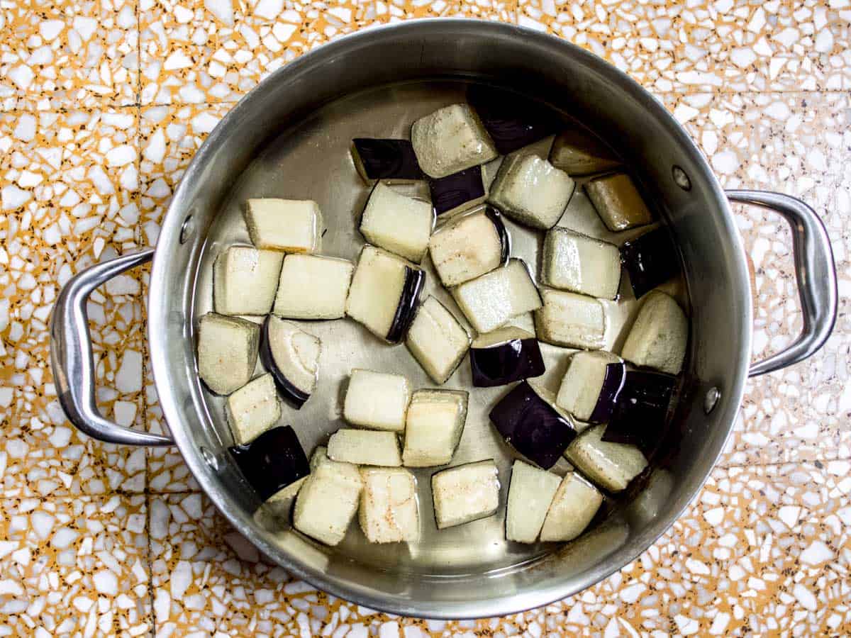 aubergine cubes in oil in a stainless steel saucepan