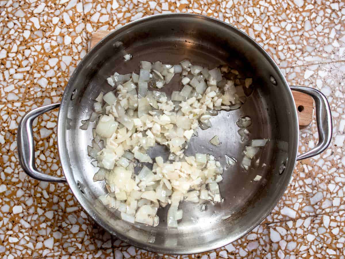 Stainless steel saucepan with finely chopped onions in oil