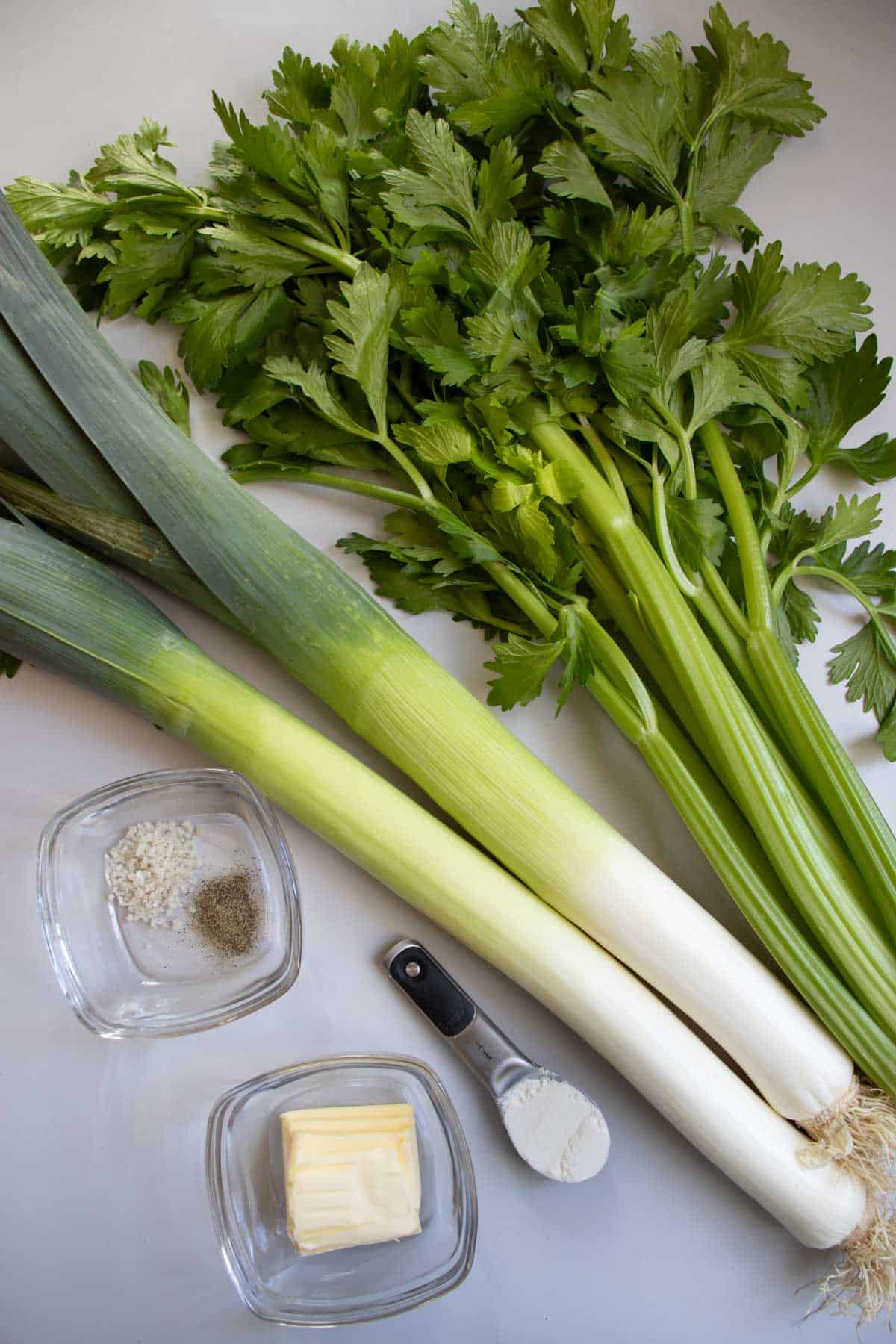 Leeks, celery, butter, salt and pepper in glass bowl, butter in glass bowl, flour in measuring spoon.