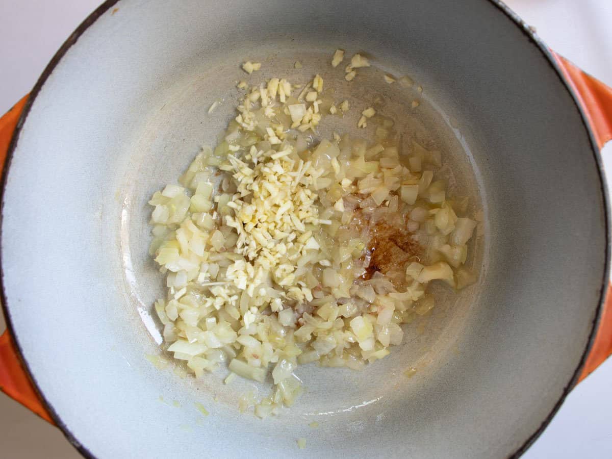 Finely chopped garlic has just been added to fried onion in saucepan.