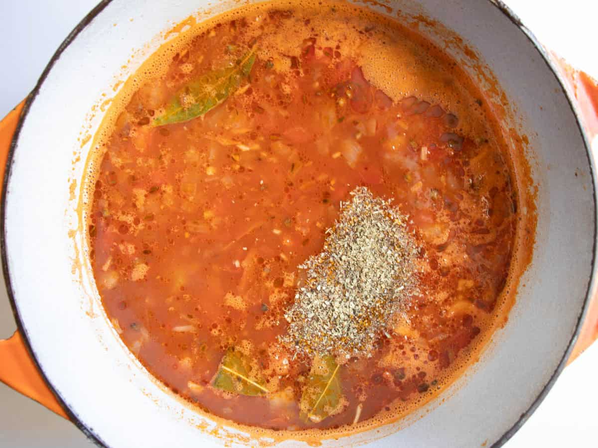 Dried marjoram has just been added to French lentil soup in enamelled cast iron saucepan.