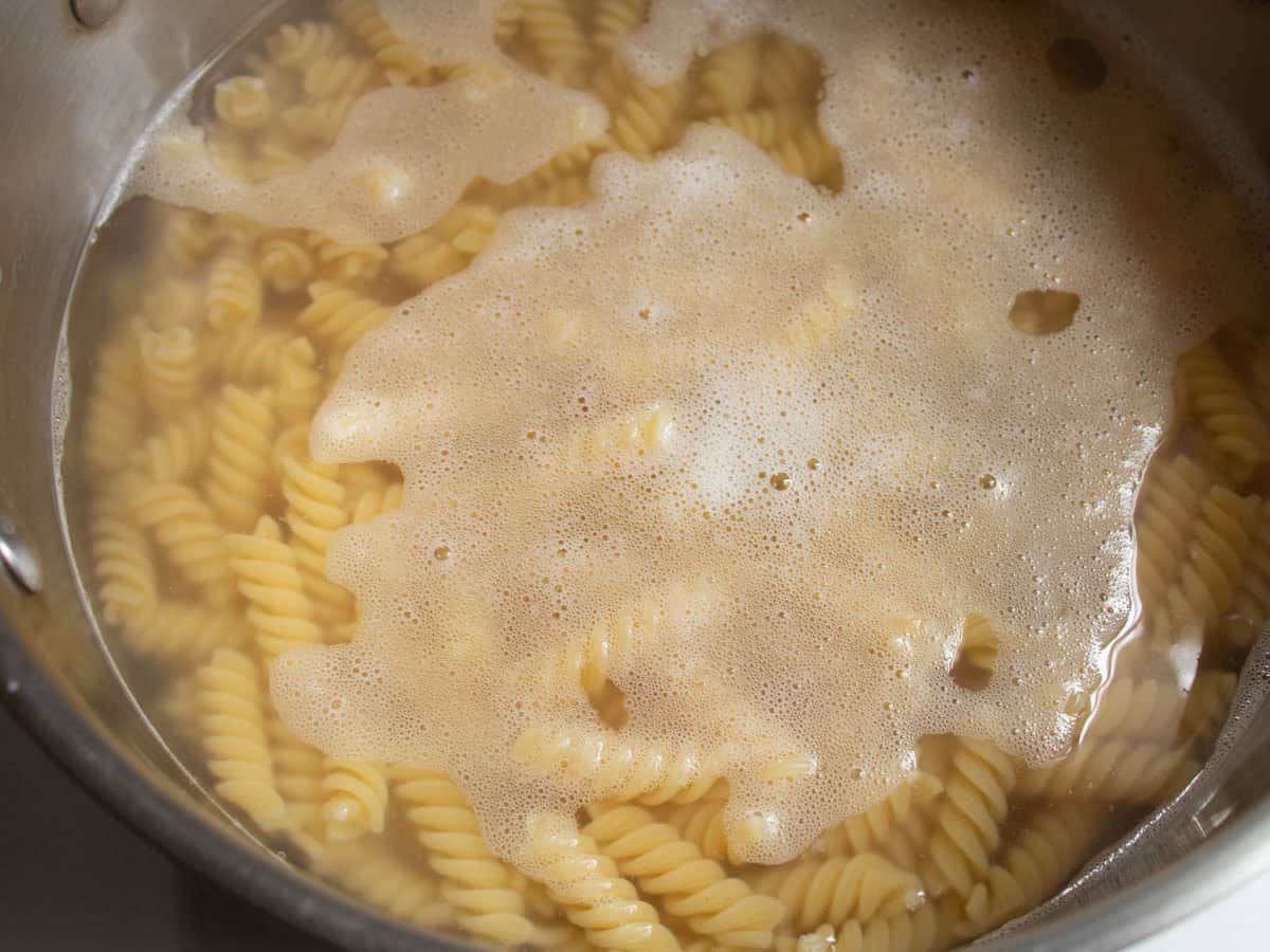 Fusilli pasta being cooked in water in a saucepan.