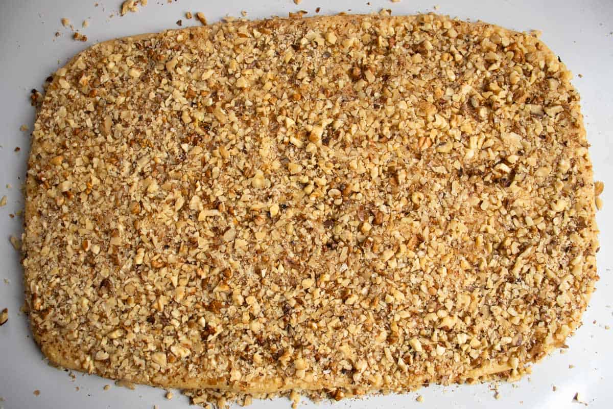 Rectangular rolled out cookie pastry covered in finely chopped walnuts.