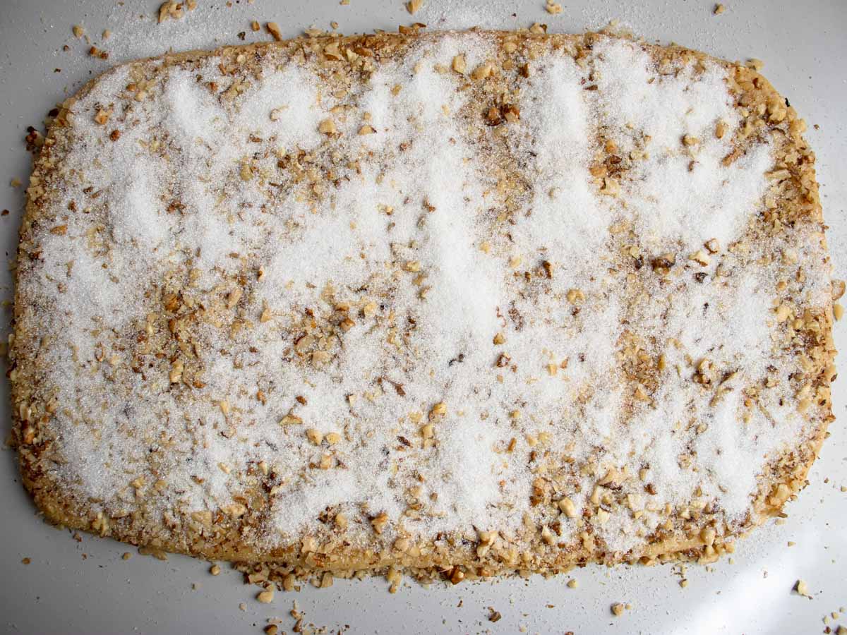 Walnut covered rolled out cookie pastry sprinkled with white sugar.