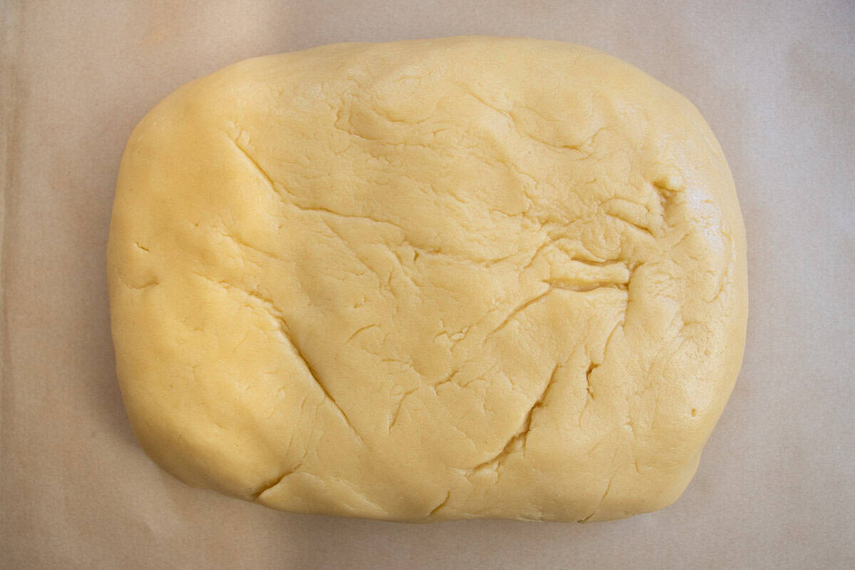 Walnut cookie dough shaped into rectangular shape on baking paper.