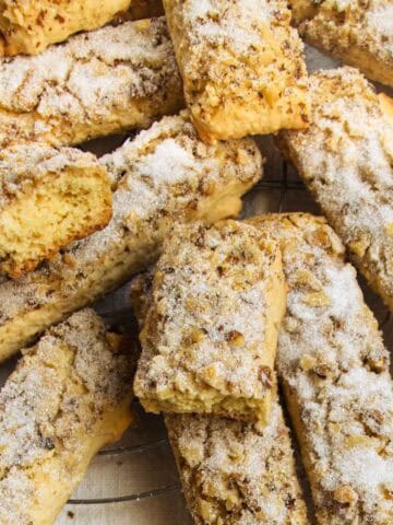 Sugar-coated walnut cookies on wire tray, one broken in half.