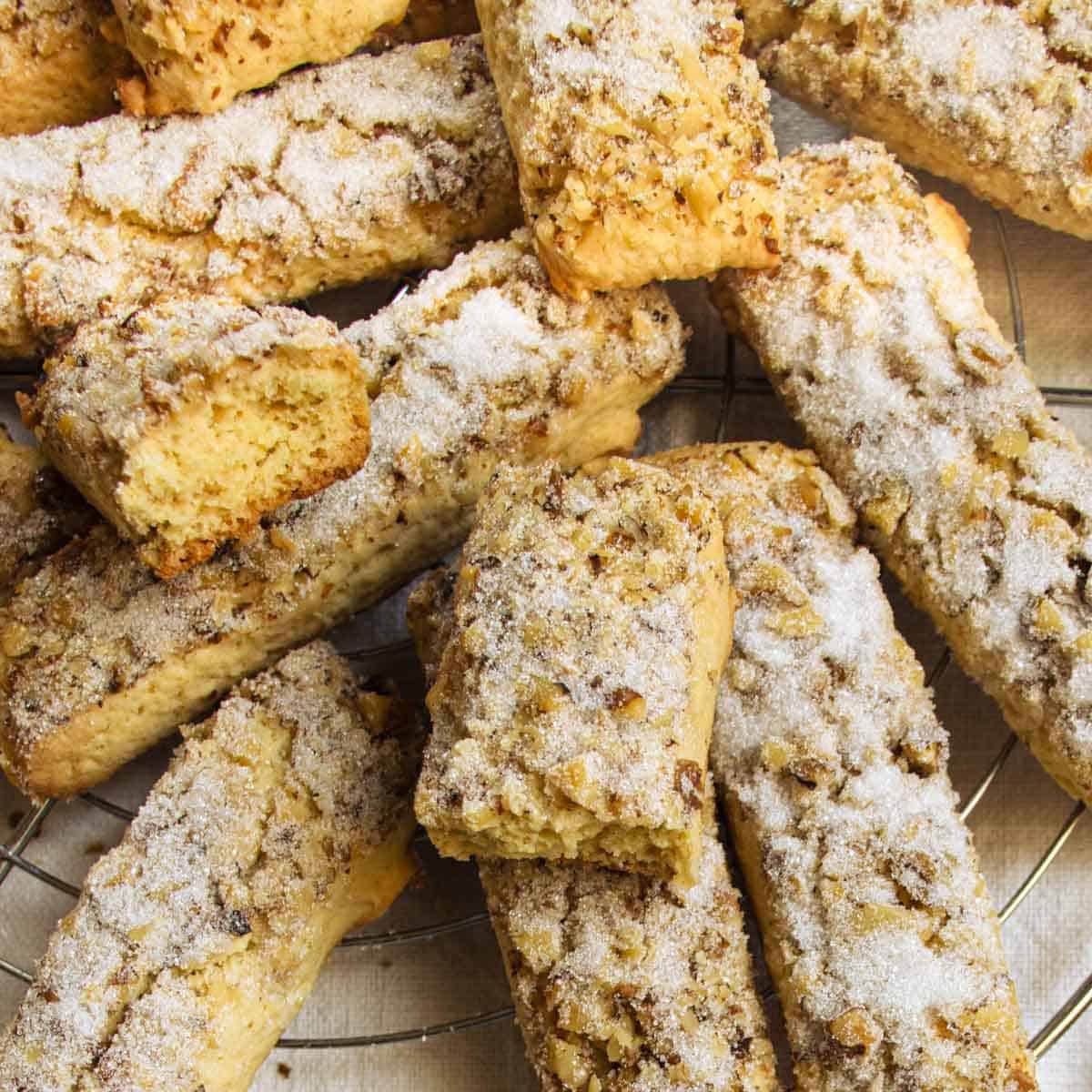 Sugar-coated walnut cookies on wire tray, one broken in half.