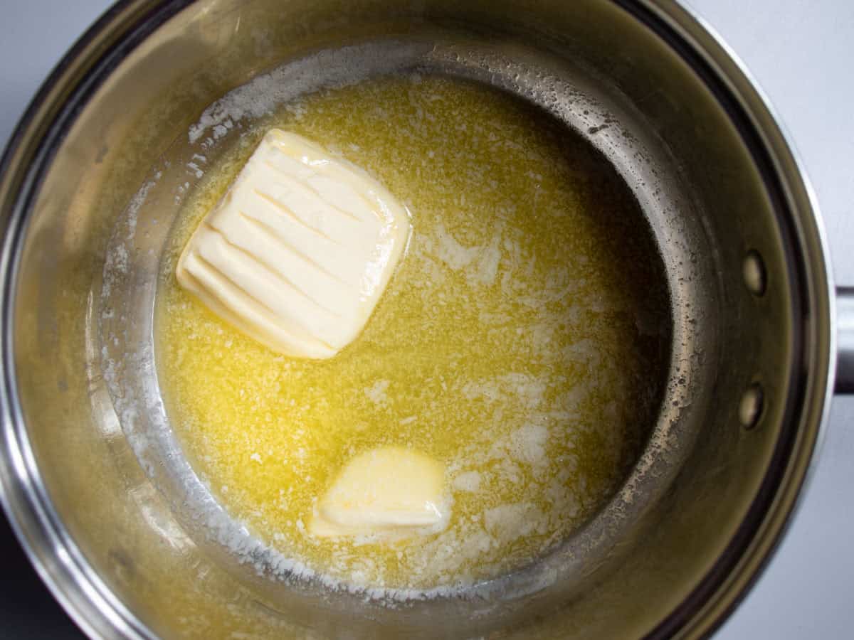 Butter being melted in stainless steel saucepan.